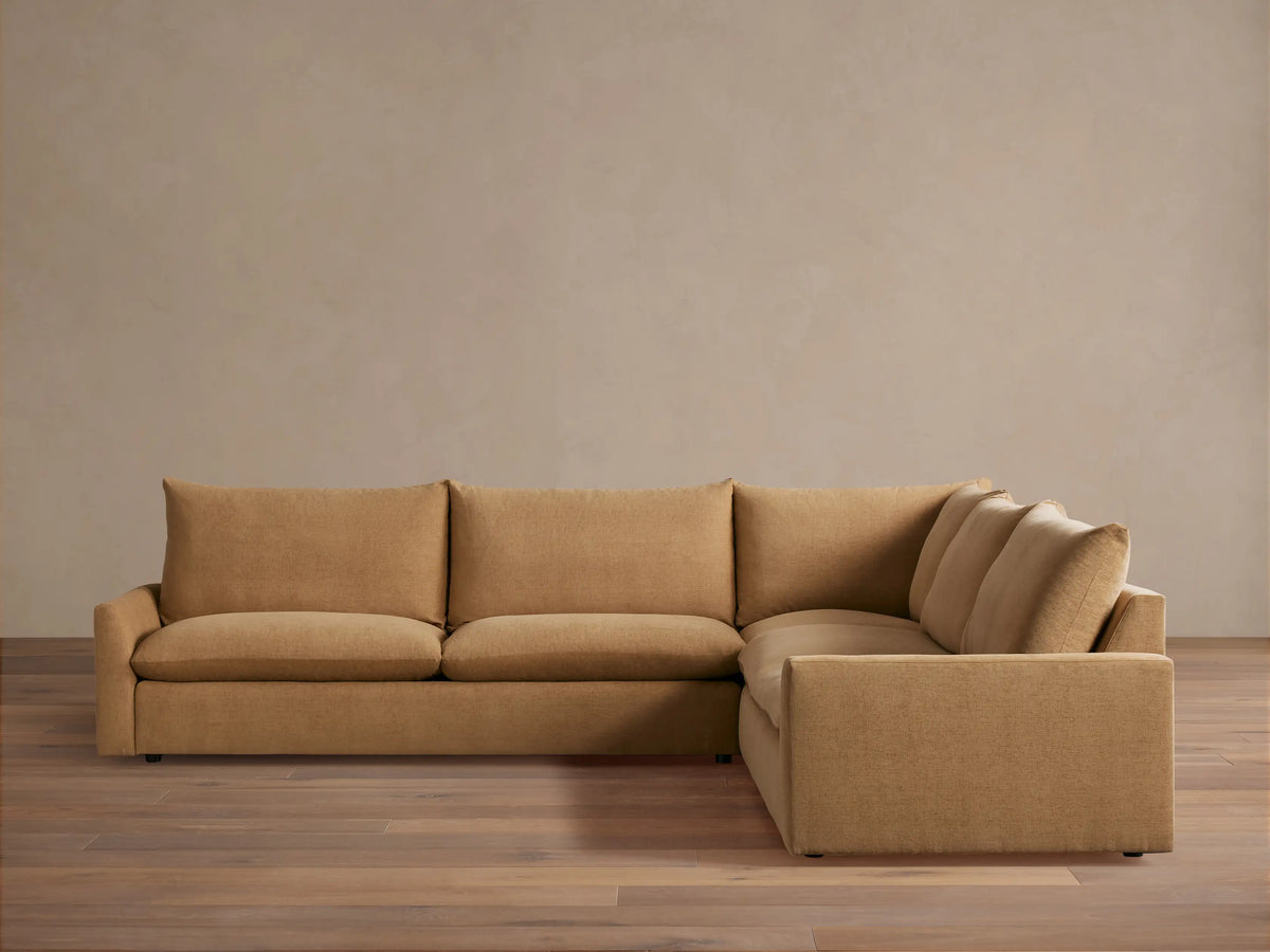 Tan-colored, L-shaped Calistoga three-piece corner sectional on a wooden floor against a neutral wall. Thick cushions and plush backrests.