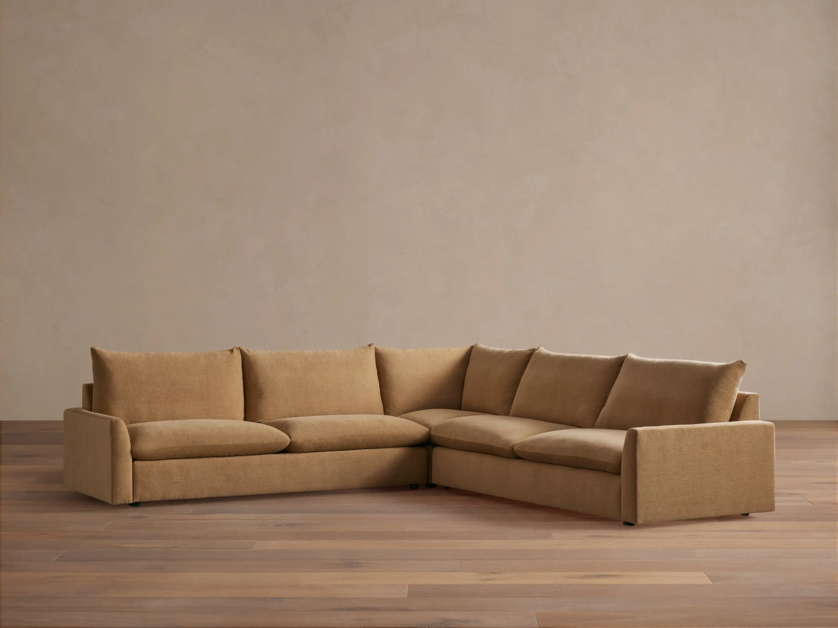 Tan-colored, L-shaped Calistoga three-piece corner sectional on a wooden floor against a neutral wall. Thick cushions and plush backrests.