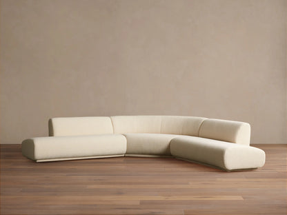 Cream Gianni Three-Piece Curved Bumper Sectional on a wooden floor against a tan wall, showing its elegant, modern design.