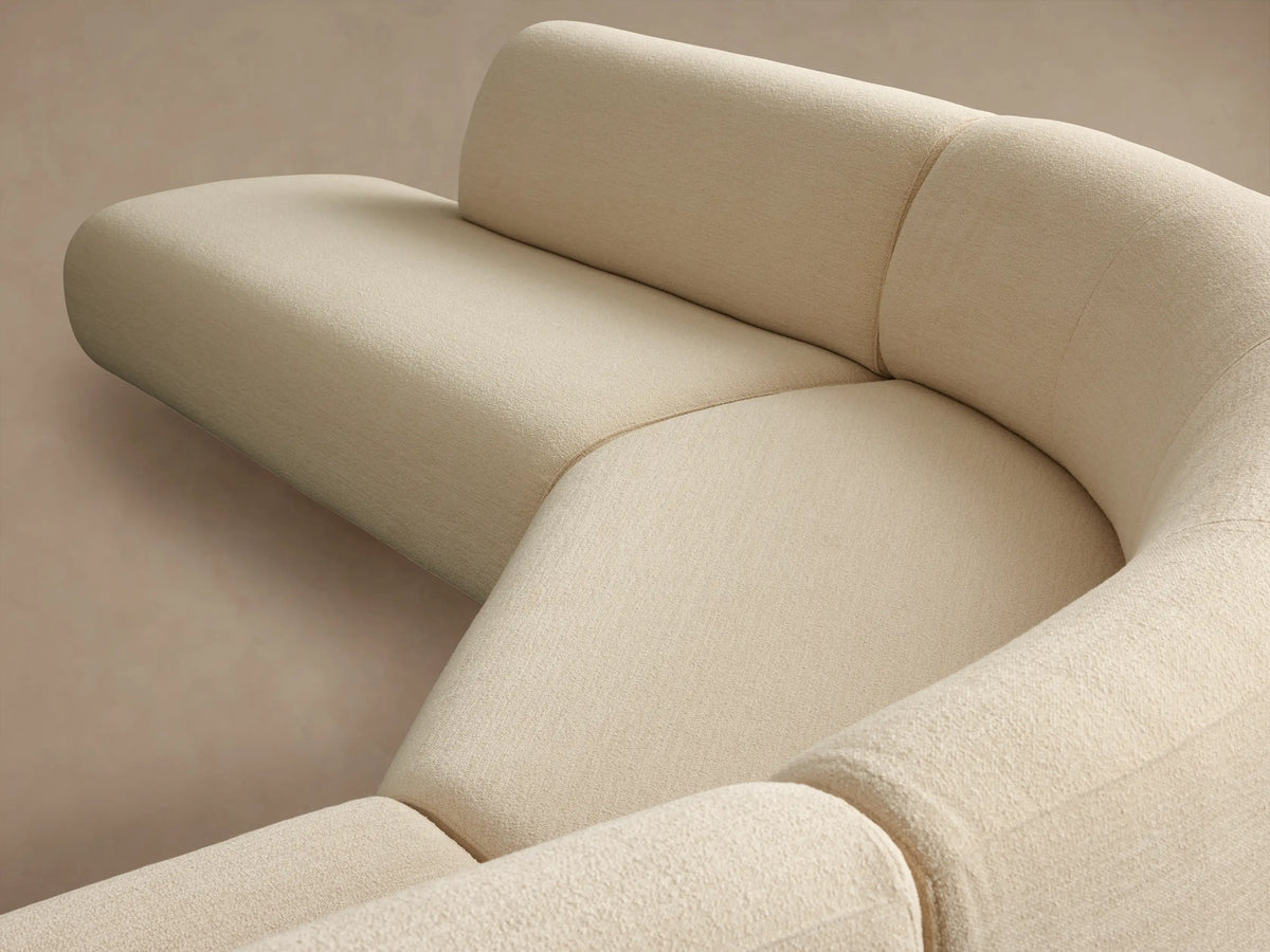 Cream Gianni Three-Piece Curved Bumper Sectional sofa on a wood floor. Modern, soft curves and rounded edges.