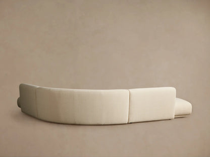 Close-up of a Gianni Three-Piece Curved Bumper Sectional, light beige textured fabric with a prominent curve, viewed from above right.