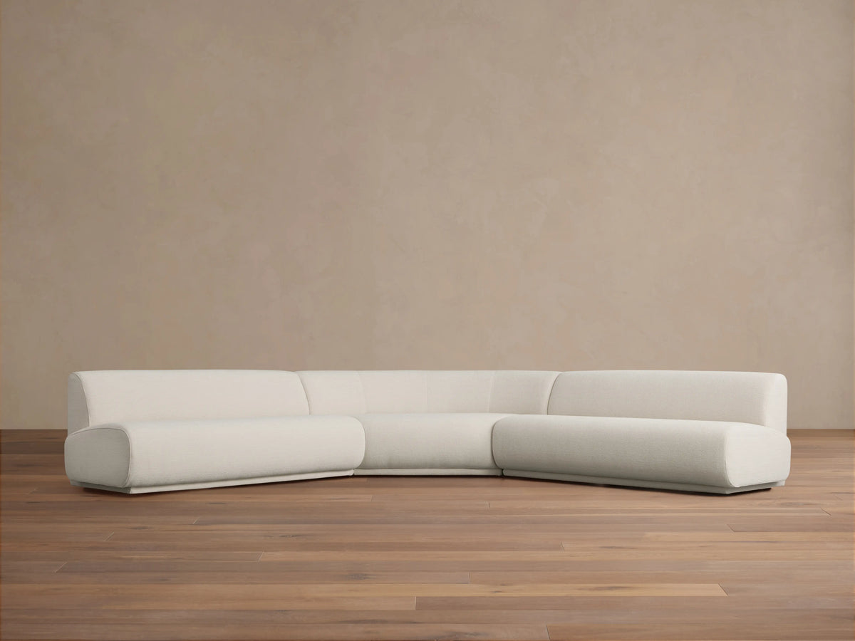 Gianni Three-Piece Corner Sectional in white fabric, featuring a modern, minimalist design. Set on a light wood floor against a beige wall.