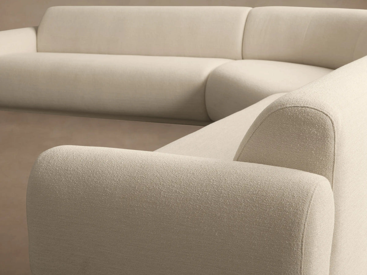 Light beige Gianni Three-Piece Corner Sectional with rounded arms and back, L-shaped, on a wooden floor against a plain wall.