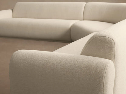 Light beige Gianni Three-Piece Corner Sectional with rounded arms and back, L-shaped, on a wooden floor against a plain wall.