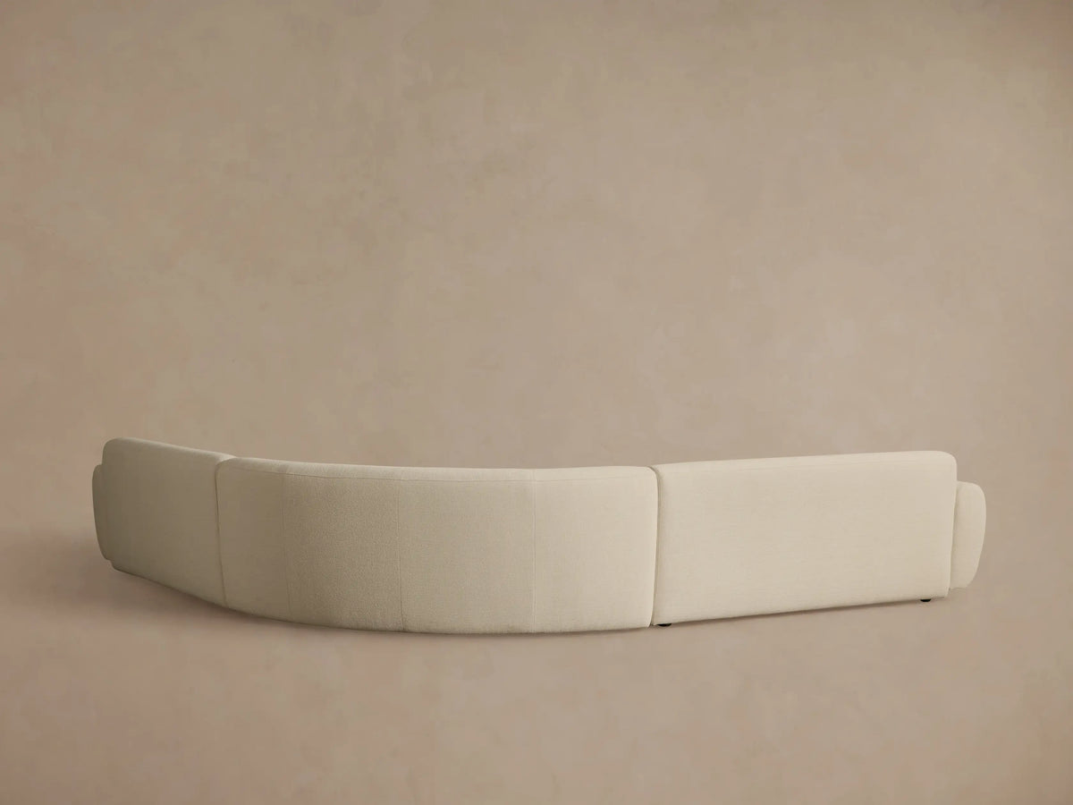 Close-up of the Gianni Three-Piece Corner Sectional, featuring a curved armrest and textured light beige fabric.