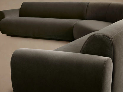 Gianni Three-Piece Corner Sectional in dark grey velvet, L-shaped with rounded armrests, viewed straight on against a tan wall.