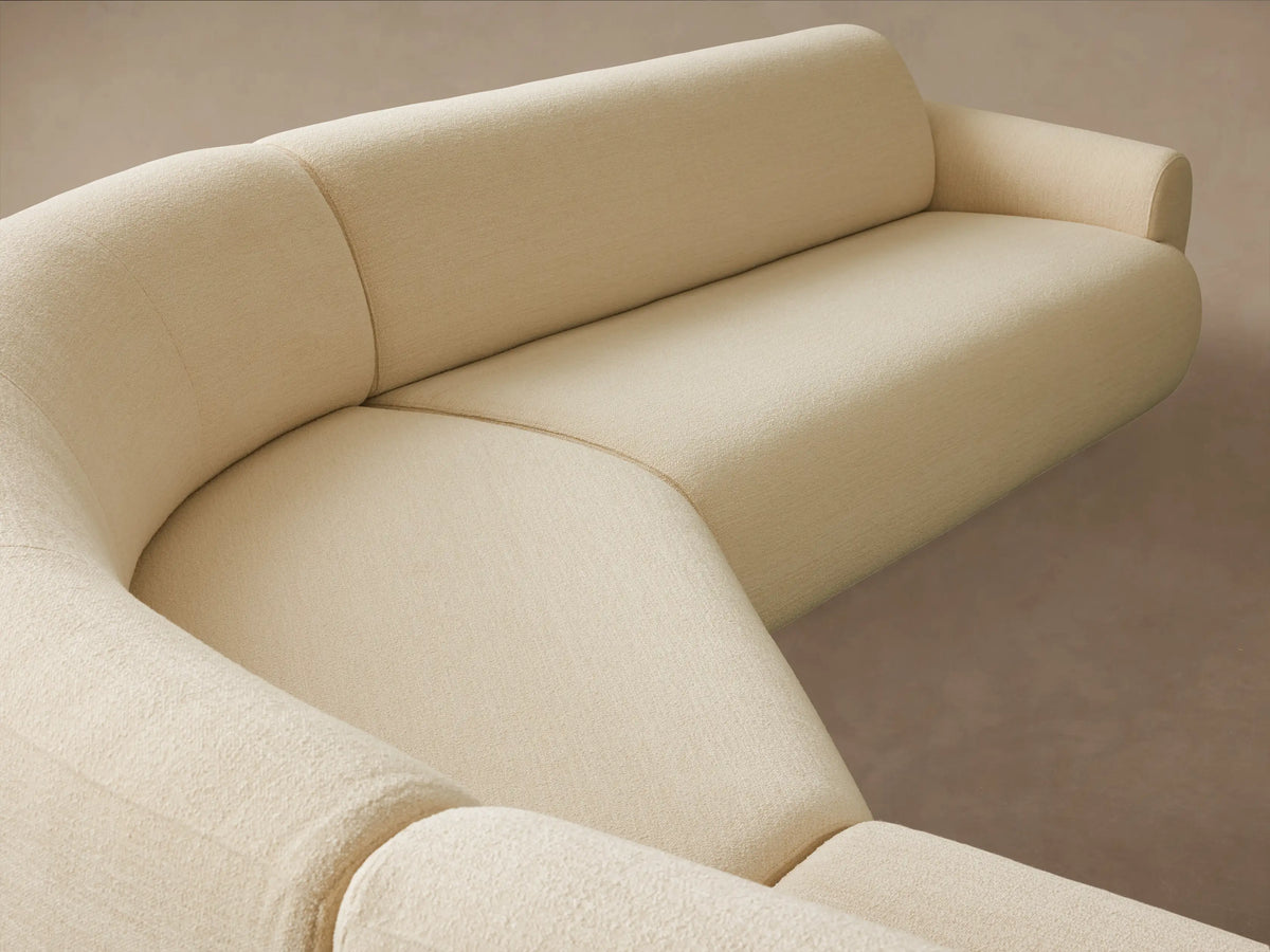 Gianni Three-Piece Bumper Sectional, L-shaped, cream upholstered, low profile with curved edges, on a wooden floor.