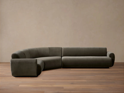 Close-up of a curved Gianni Three-Piece Sectional sofa in dark grey velvet, showing the channel-tufted back.