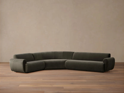 Deep taupe Gianni Three-Piece Sectional with a distinctive curved design, featuring multiple throw pillows, arranged in a spacious room.