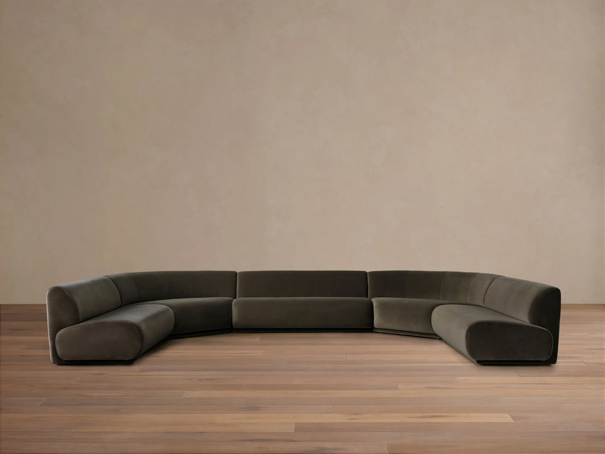 Dark olive green Gianni Five-Piece Armless Curved Sectional in a deep U-shape, resting on a wood floor against a neutral wall.