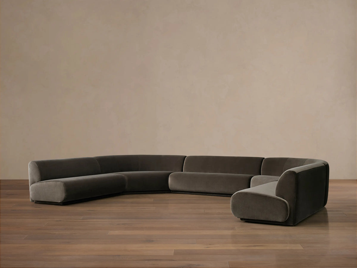 Dark olive green Gianni Five-Piece Armless Curved Sectional in a deep U-shape, resting on a wood floor against a neutral wall.