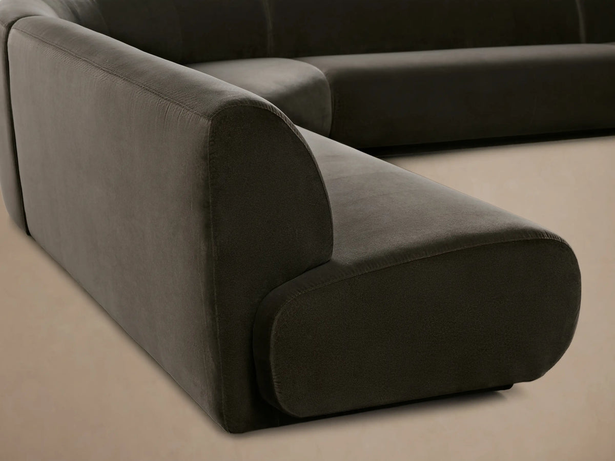 Gianni Five-Piece Armless Curved Sectional sofa in dark grey velvet, with smooth, low profile, on a wooden floor.