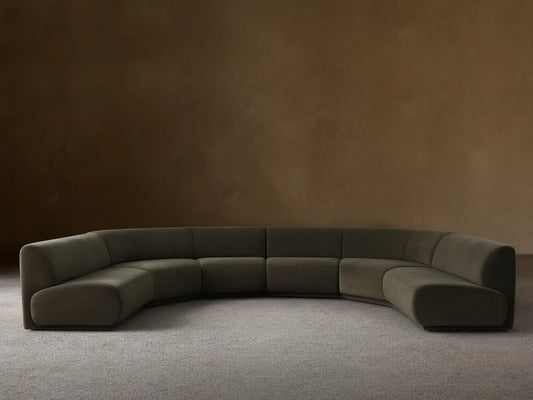 Dark olive green Gianni Five-Piece Armless Curved Sectional in a deep U-shape, resting on a wood floor against a neutral wall.