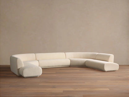 Cream Gianni Five-Piece Curved Bumper Sectional, low-profile and modular, on wood floor against a plain wall.