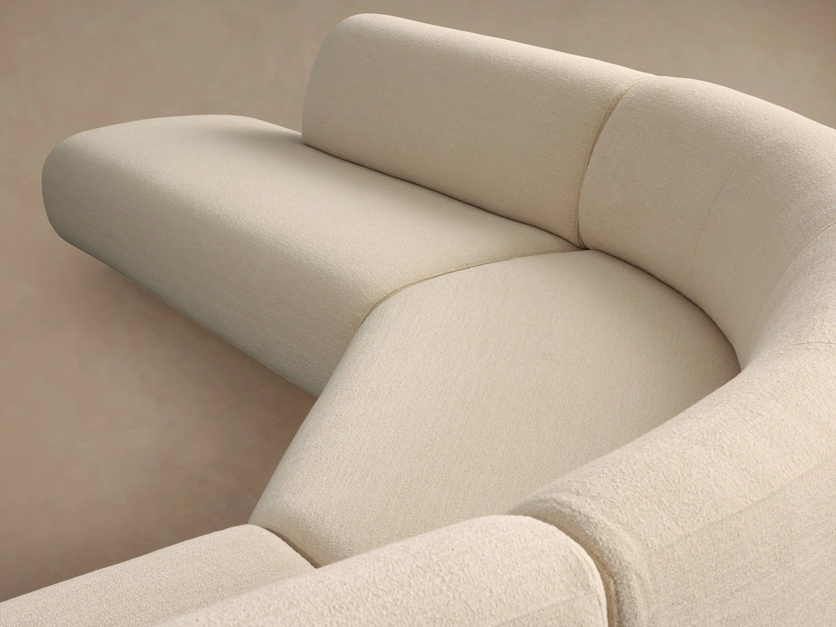 Cream Gianni Five-Piece Curved Bumper Sectional, forming a wide curve, on a wooden floor against a beige wall.