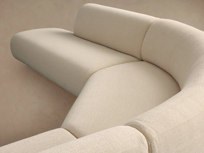 Cream Gianni Five-Piece Curved Bumper Sectional, forming a wide curve, on a wooden floor against a beige wall.
