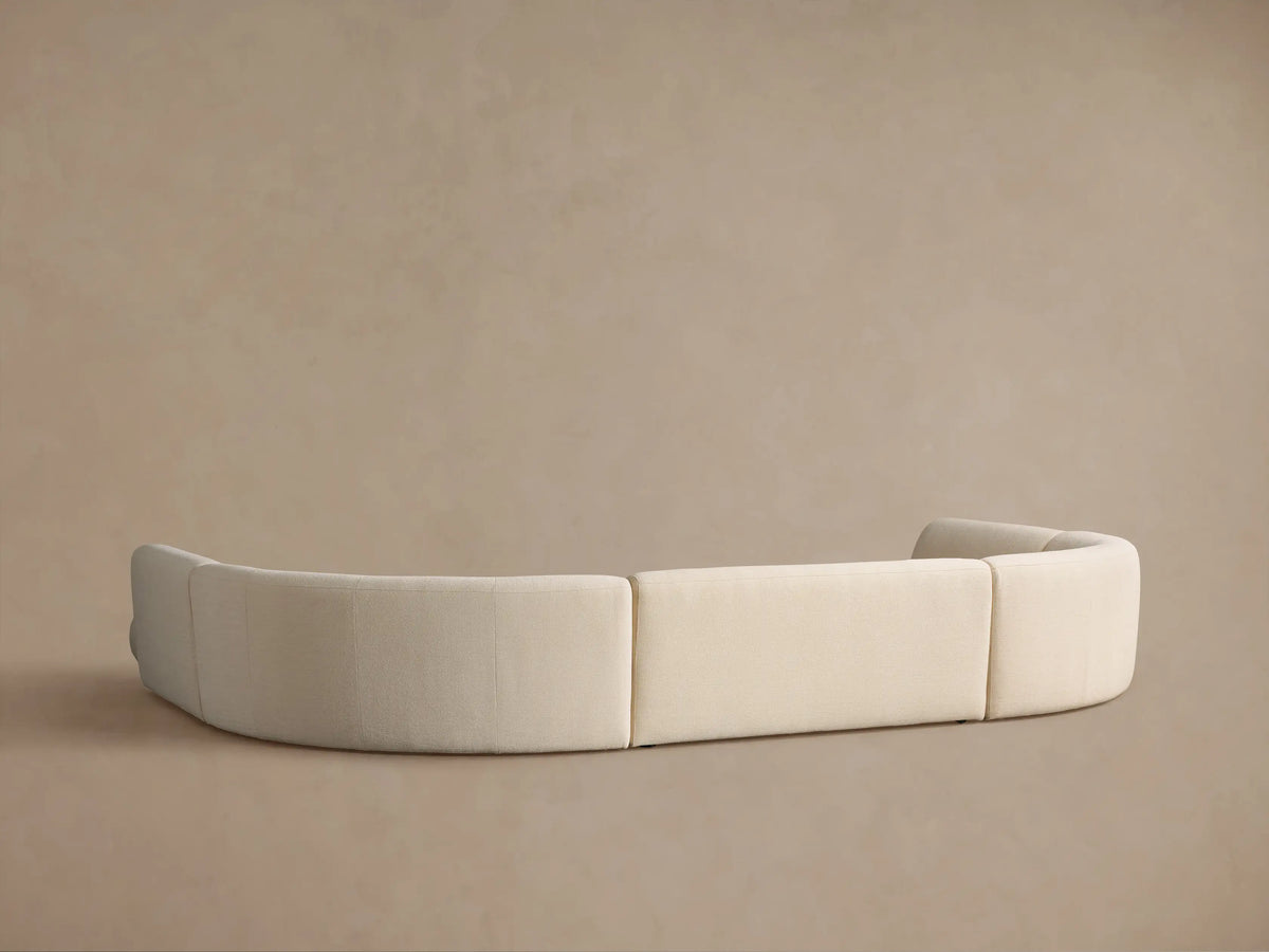 Elevated view of a Gianni Curved Bumper Sectional, light cream, textured fabric, showing its seamless, flowing design.