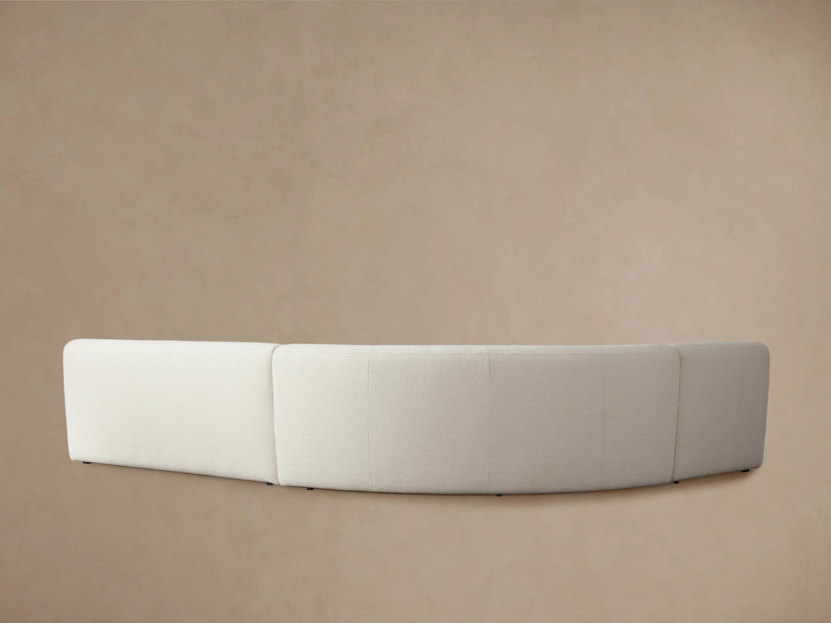 Cream-colored Gianni Three-Piece Sectional with curved edges, plush upholstery, and visible stitching on smooth fabric against a neutral background.