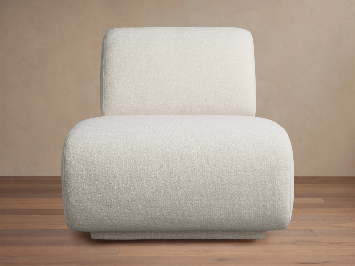 Gianni Swivel Chair in a textured, creamy white fabric, shown front-facing. Features a rounded, plush seat and backrest on a wooden floor.