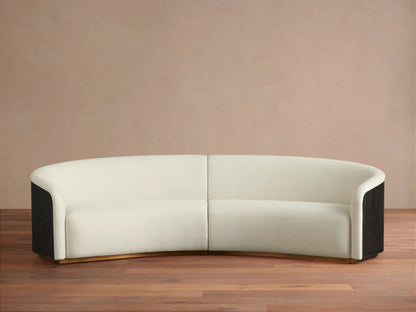 Finnley Two-Piece Curved Sectional in cream fabric, with dark fluted arm ends, and a golden base, on a wood floor.