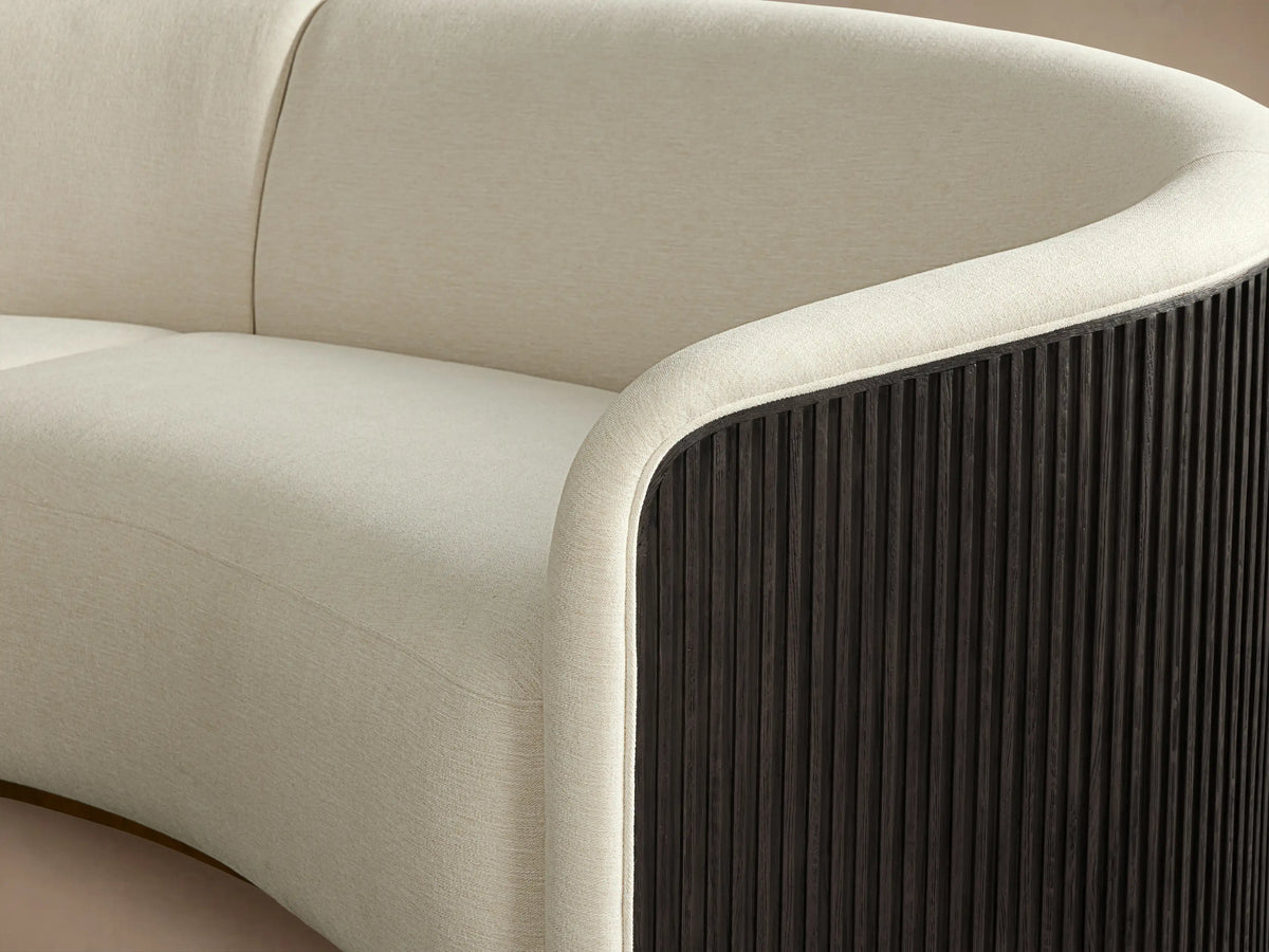 Finnley Two-Piece Curved Sectional in cream fabric with a sleek, modern design. Features rounded corners, black accents, and wooden floor.