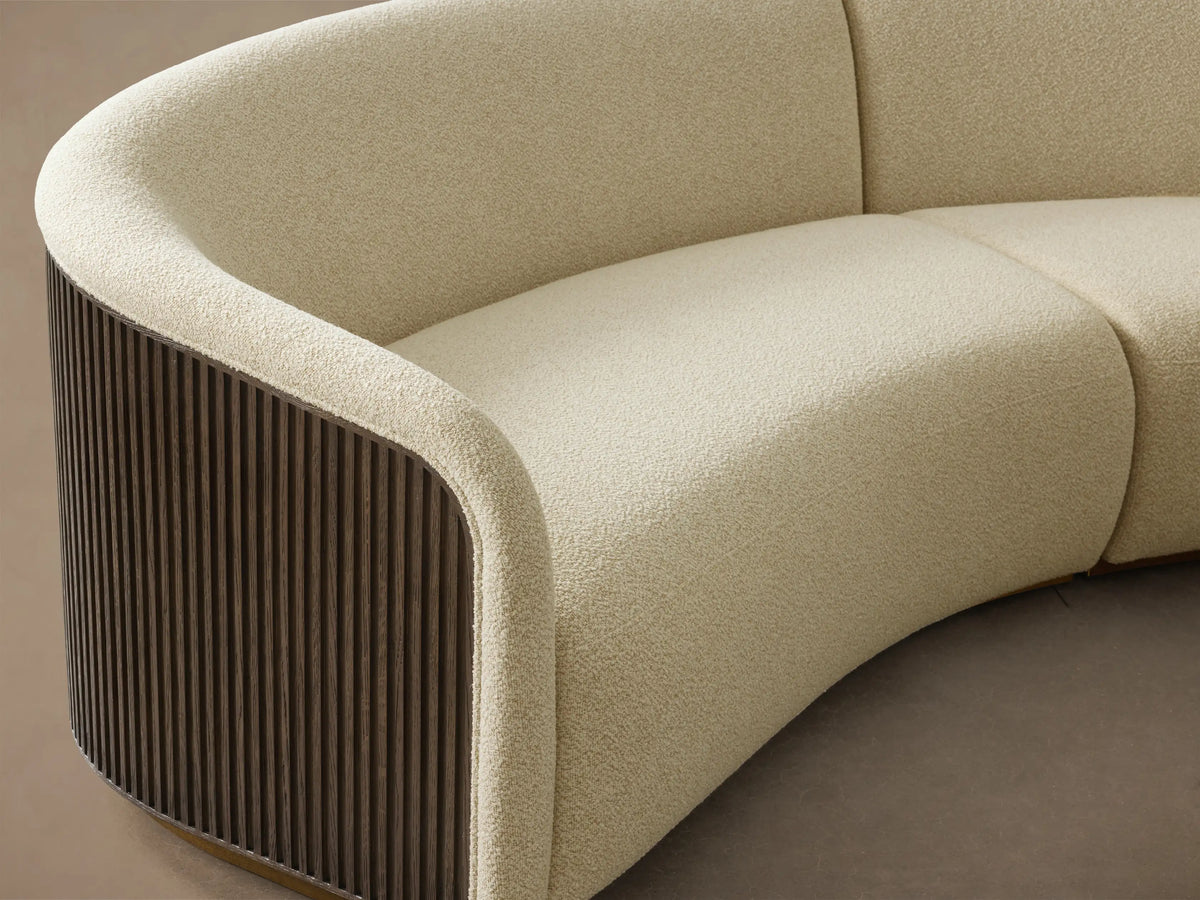 Front view of the cream boucle Finnley Two-Piece Curved Sectional with dark wood slatted ends and a light wood base.