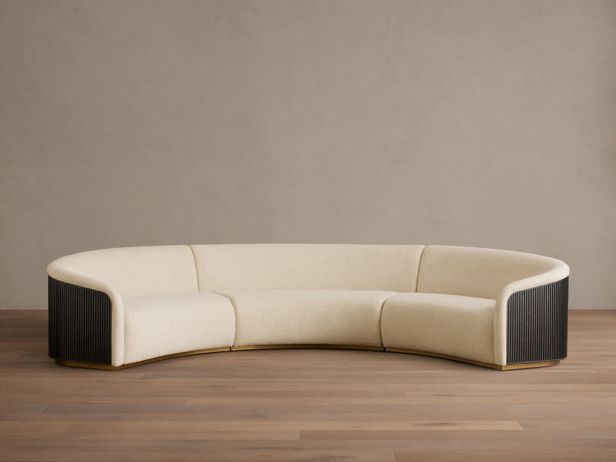 Front view of an Ecru Finnley Three-Piece Curved Sectional with black slatted armrests and a golden base.