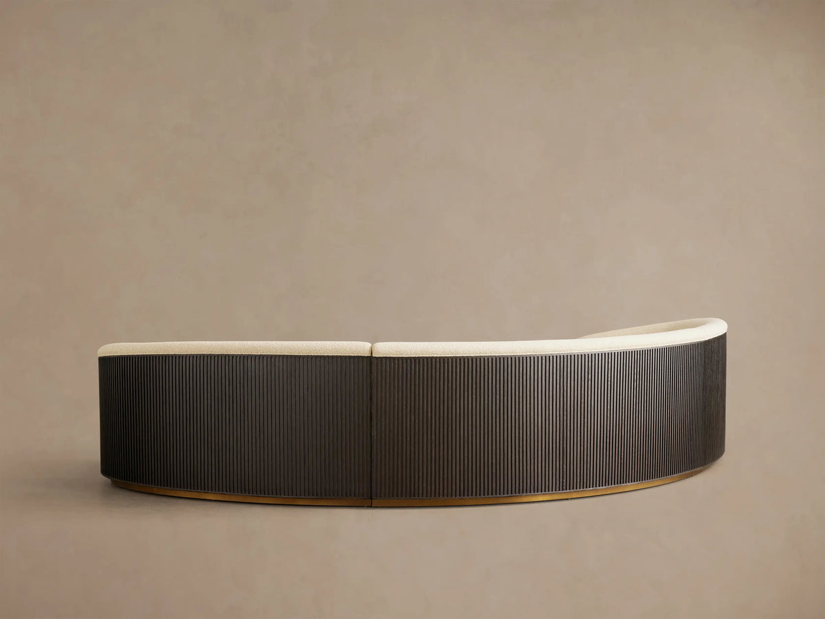 Front view of an Ecru Finnley Three-Piece Curved Sectional with black slatted armrests and a golden base.