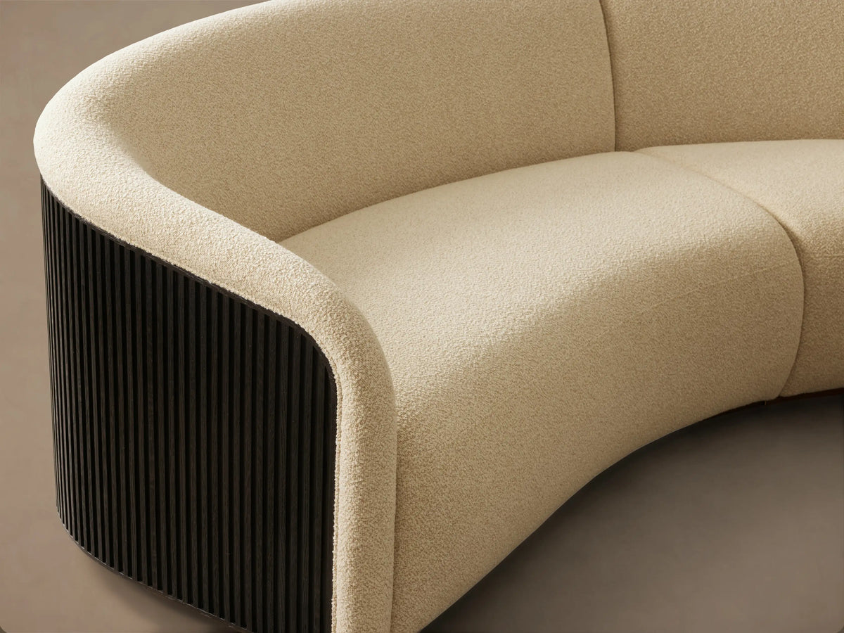 Side profile of the Finnley Three-Piece Curved Sectional with dark fluted back, light cream upholstery, and light wood base.