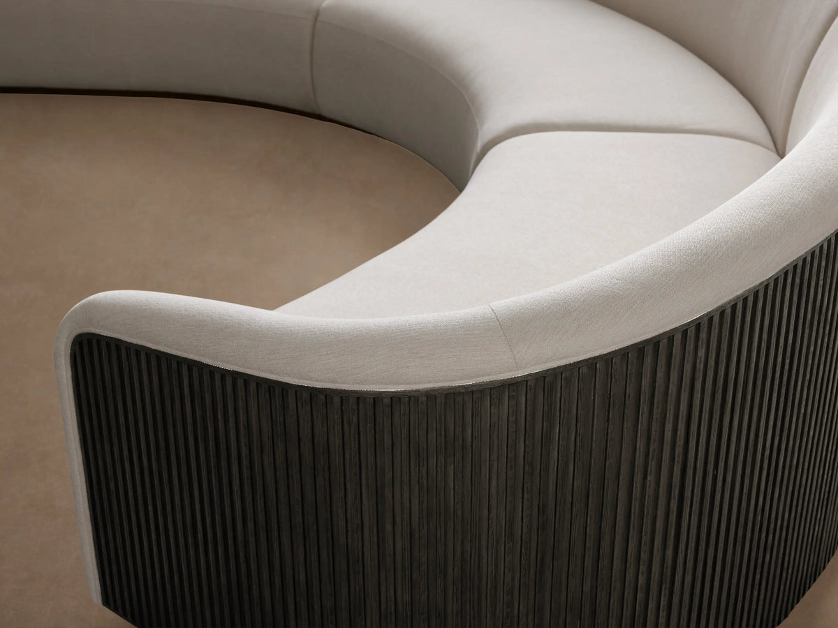 Curved three-piece Finnley sectional with cream-colored upholstery, black ribbed wooden side panels, and light wood flooring.