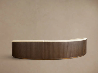 Rear view of the Finnley Three-Piece Curved Sectional, featuring an Ebony wood ribbed base and light beige fabric upholstery.