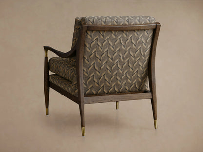 Fisher Chair close-up. Dark mocha wood & brass armrest with intricate grey & beige leaf-patterned fabric upholstery.