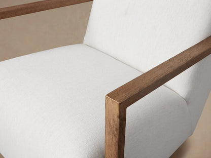 Walsh Glider chair with white fabric upholstery, wooden armrests, and a swivel base on a wooden floor, viewed from the front.