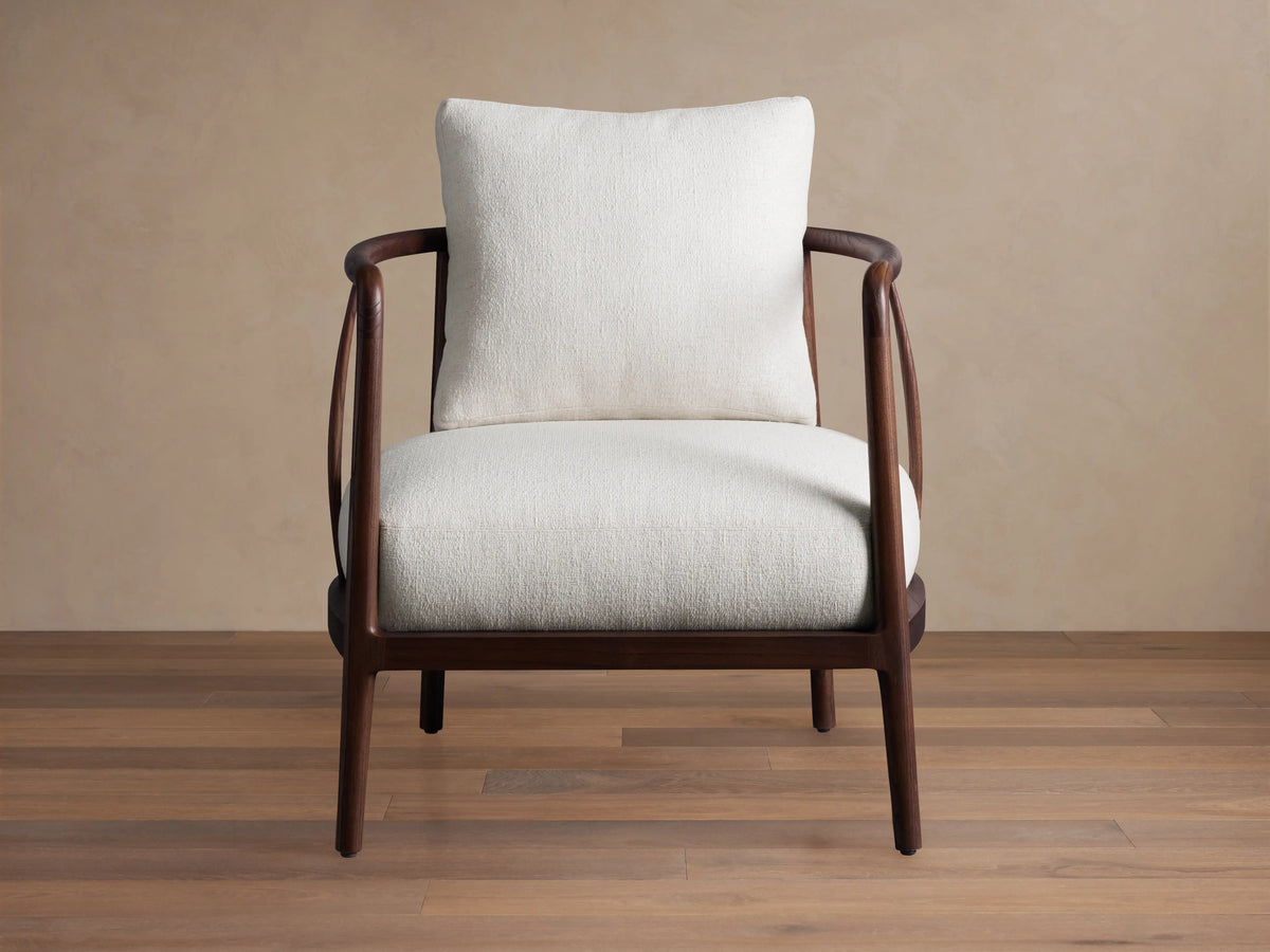 Griggs Chair with dark mahogany wood frame, curved arms, and plush cream upholstery, set on a wooden floor.