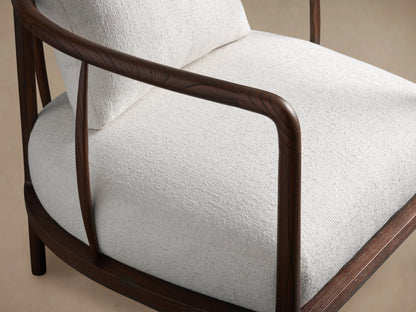 Griggs Chair with dark mahogany and sungkai wood frame. Light-colored upholstery. Curved armrests and cushioned back and seat.
