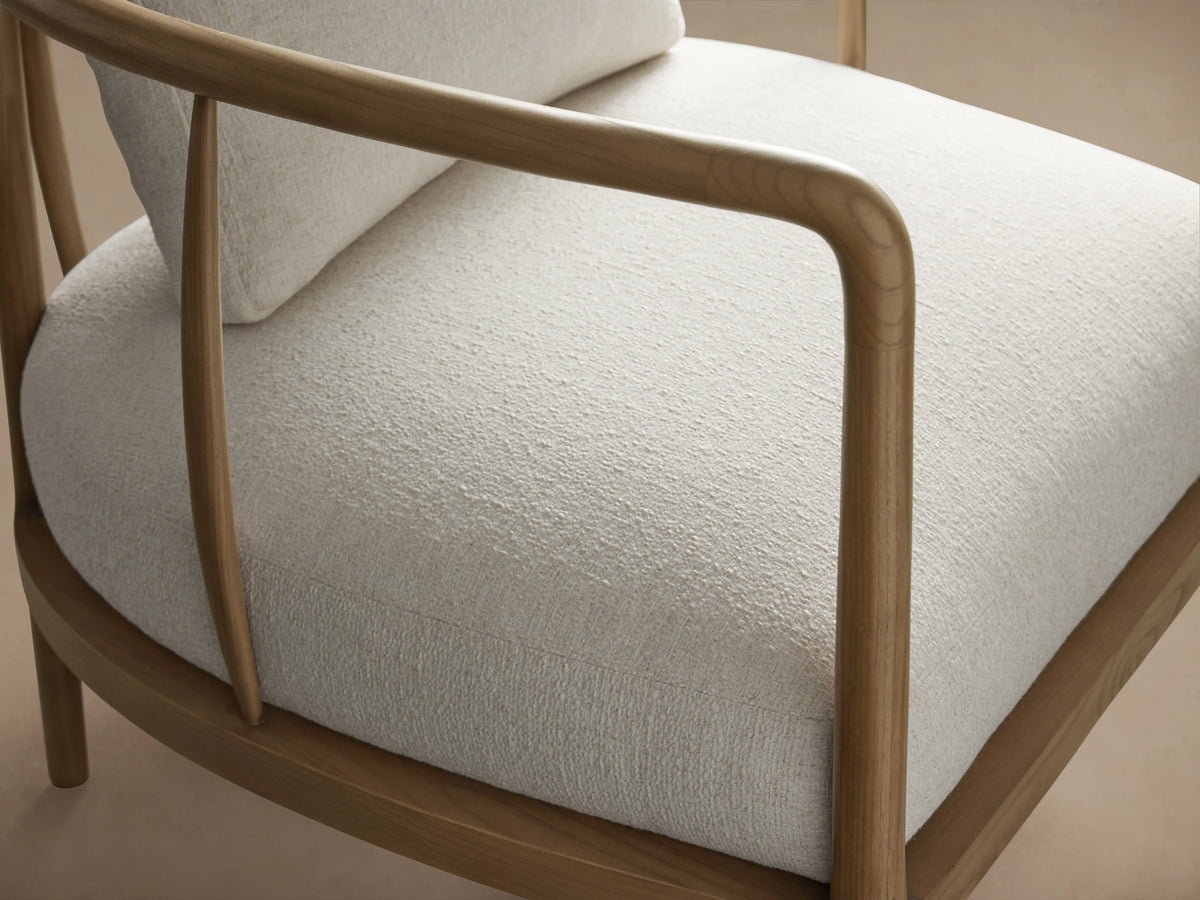 Griggs Chair with light upholstery and solid mahogany frame, featuring curved armrests on a wooden floor.