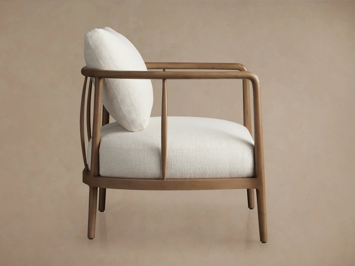 Griggs Chair featuring light-colored plush upholstery on a curved wood frame with a smooth, natural finish.