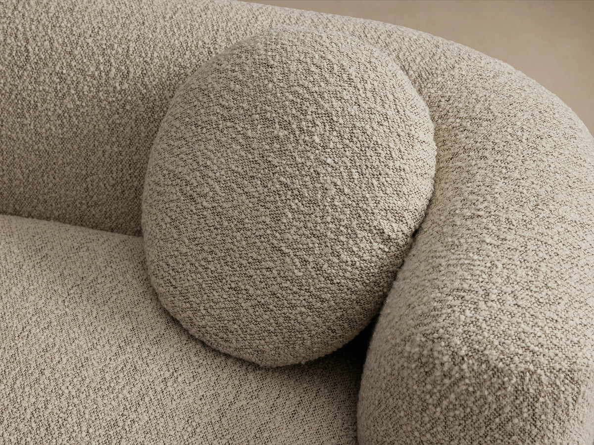 Marcela Sofa in beige textured upholstery with sleek, rounded arms and backrest; includes subtle wooden base, two round cushions.