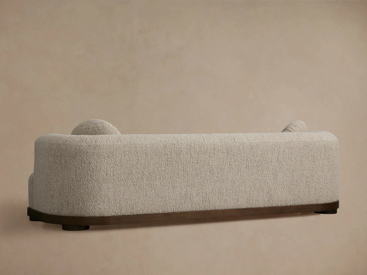 Close-up of Marcela Sofa showing a textured beige fabric with a curved armrest and round cushion, highlighting plush and cozy design.