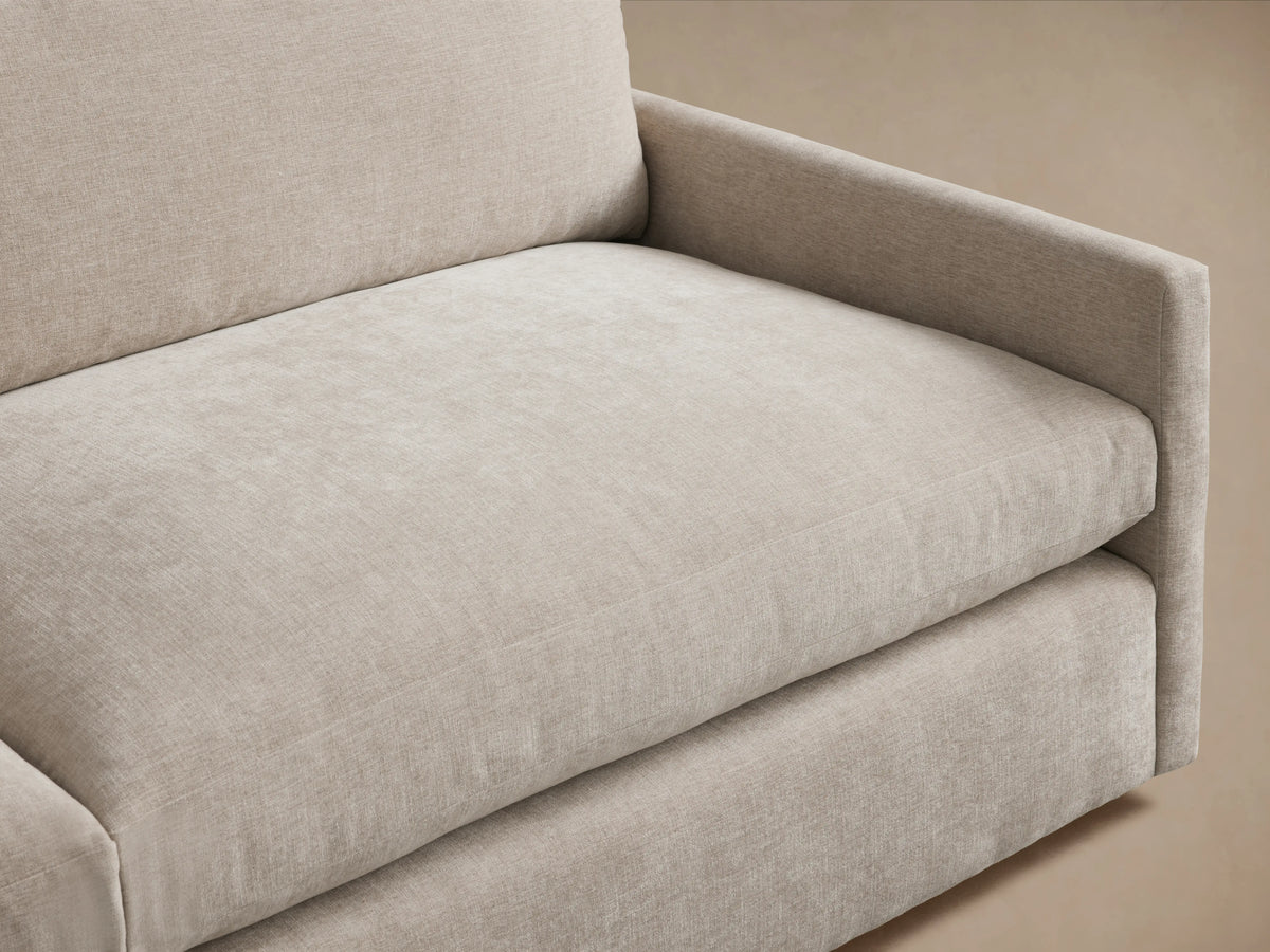 Kipton Two-Piece Sectional in neutral beige fabric on a wooden floor. The sectional has squared armrests and plush seat cushions with a backrest.