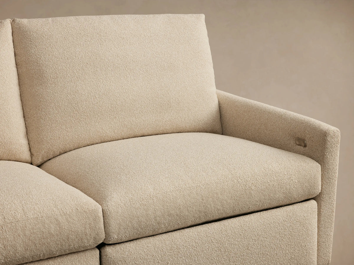 Beige fabric armrest of the Kipton modular sofa, featuring a silver two-button motion control.