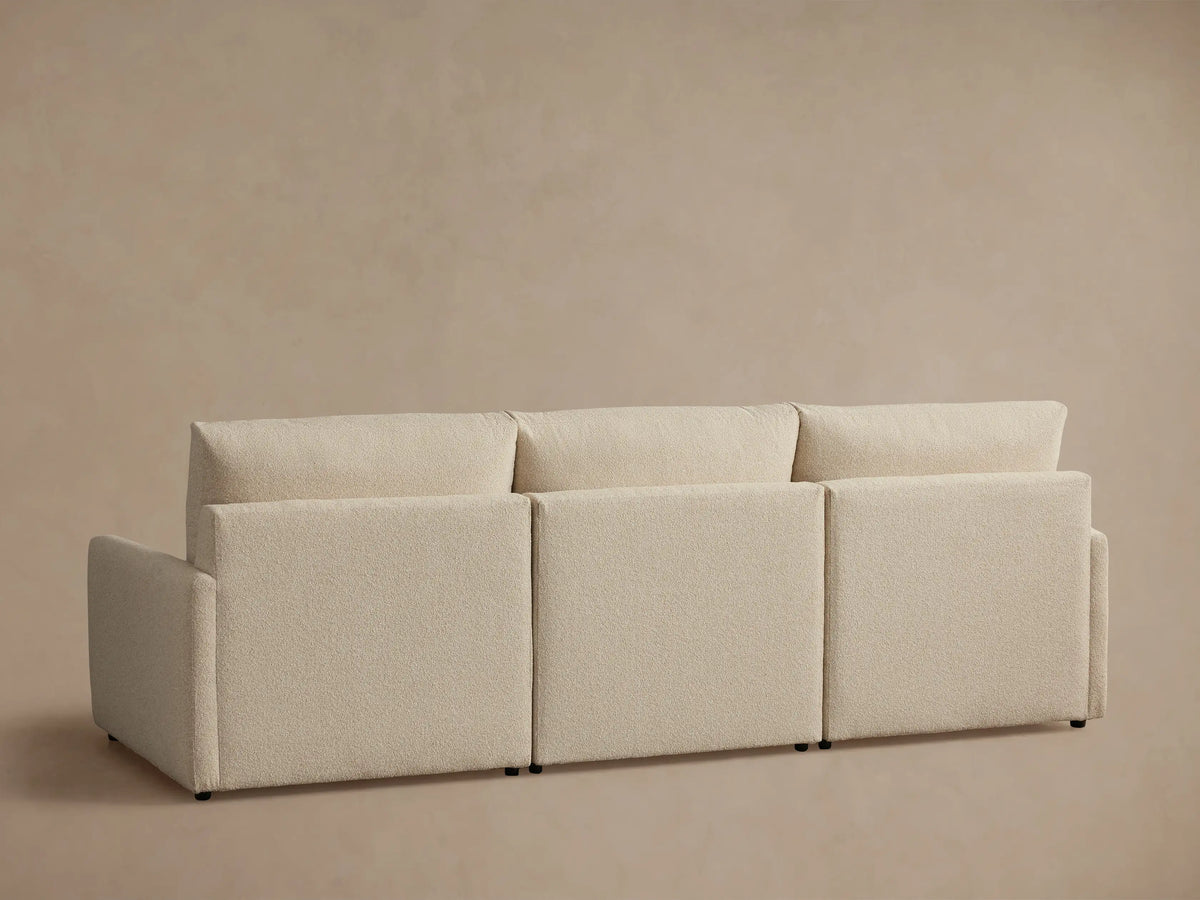 Beige Kipton Three-Piece Motion Modular Sofa with slim arms. Close-up of cushioned seat and backrest. Button control on arm.
