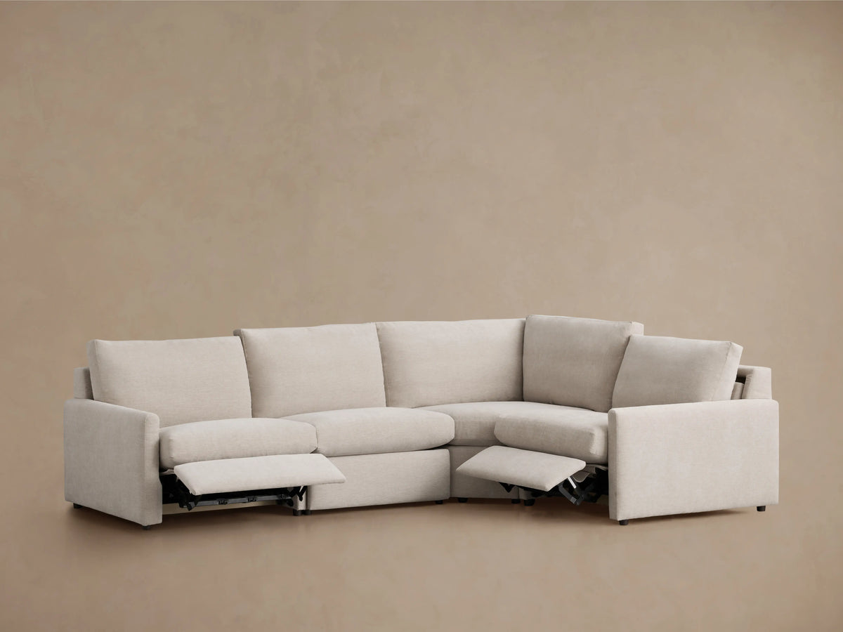 Kipton Four-Piece Motion Sectional in light beige fabric, featuring slim arms. Left section reclines with visible footrests extended.