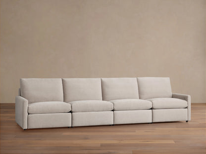 Kipton Four-Piece Motion Modular Sofa, light beige fabric, slim arms, four seats, and high backrests on wooden floor against a beige wall.