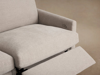 Kipton four-piece modular sofa with slim arms, upholstered in light beige fabric. Set in a wood-floored room with beige walls.