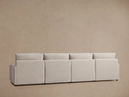 Light beige Kipton Four-Piece Motion Modular Sofa close-up showing the right armrest with a reclining button and footrest extended on a tan floor.