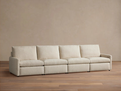 Kipton Four-Piece Motion Modular Sofa in beige fabric, viewed from the front. Features slim arms, four cushioned seats, and backrests, on a wooden floor.