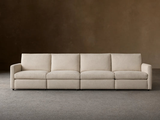Kipton Four-Piece Motion Modular Sofa in beige fabric, viewed from the front. Features slim arms, four cushioned seats, and backrests, on a wooden floor.