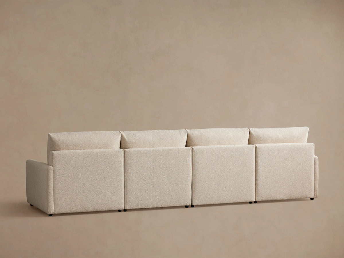 Kipton Four-Piece Motion Modular Sofa in a light beige fabric, featuring sleek, slim arms. The seat and backrest appear plush and cushioned.
