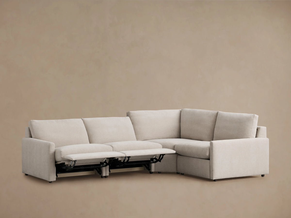 Alt text: Rear view of the Kipton Four-Piece Motion Sectional in beige fabric. The sectional features slim arms and plush cushions, with a clean, modern design.